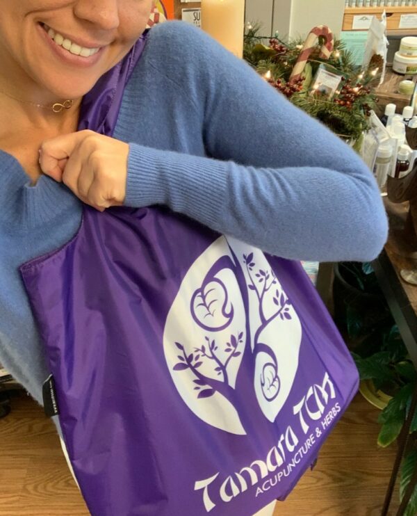 Happy woman holding a colorful 'Tamara TCM' Envirosax reusable bag over her shoulder